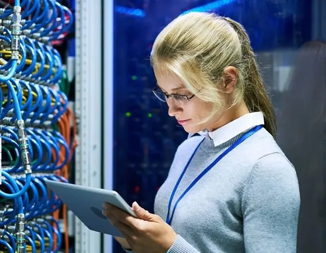 A woman is holding her tablet in front of some wires.