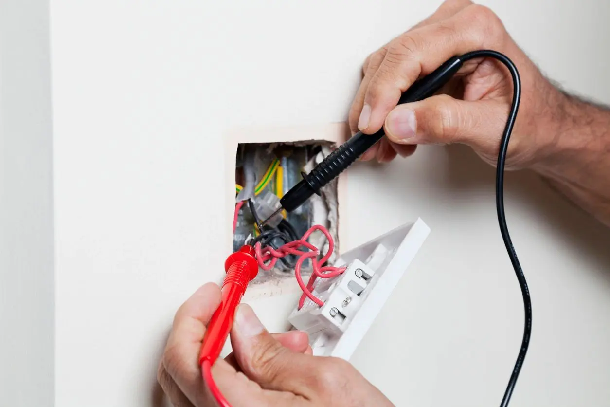 A person is cutting the wires of an electrical box.